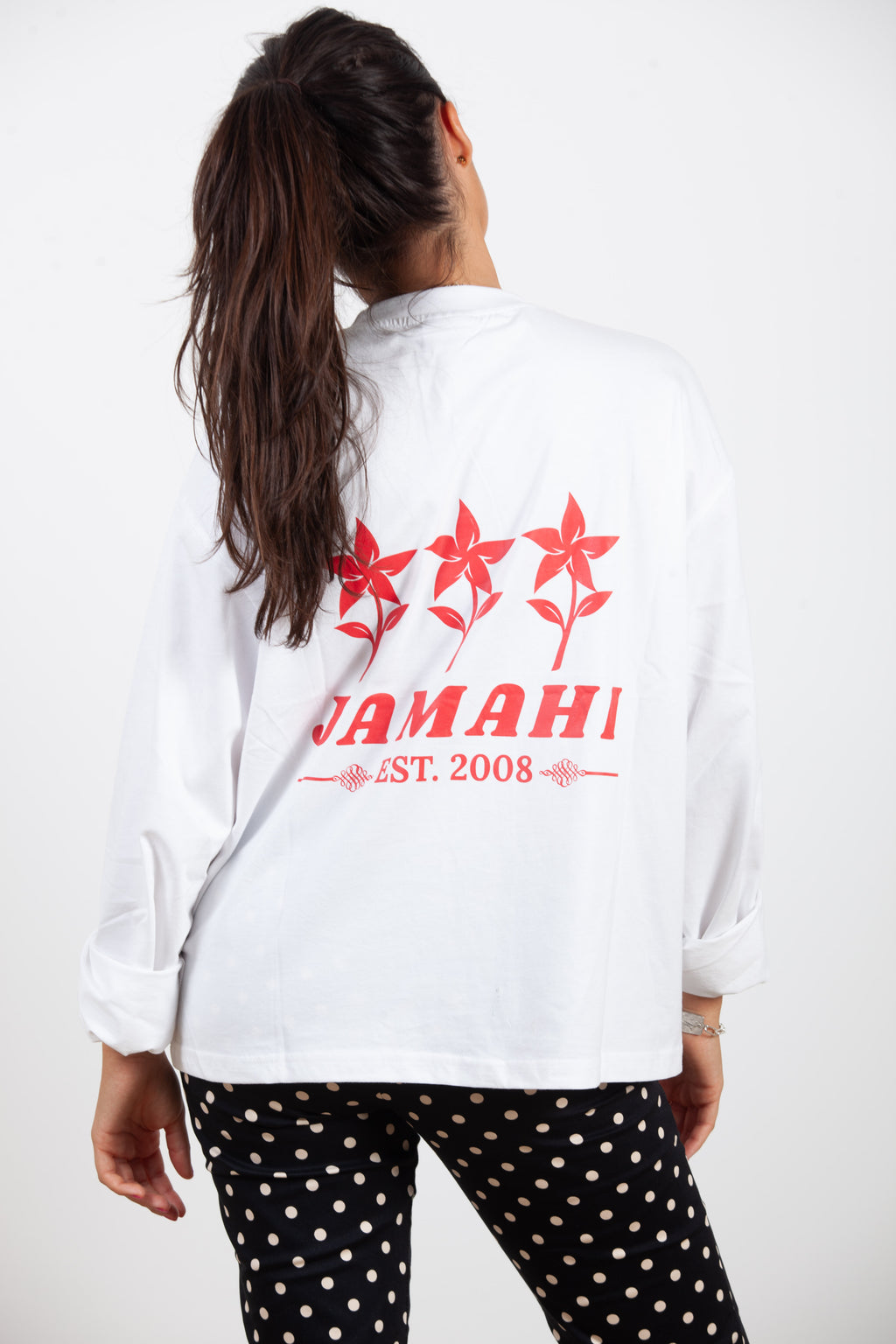 Espalda de la long sleeve blanca de Jamahi con tres flores rojas y logo Est. 2008